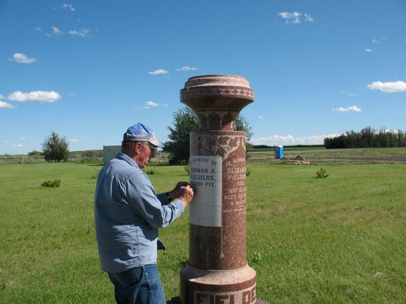 A worker with a charitable group called the Last Post Fund marks the name of Pte. Norman Fielders on the Fielders&#8217; family memorial at the Poplar Lake cemetery near the