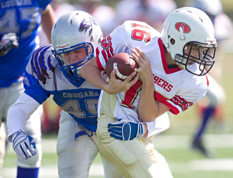 Tyler Beck of the St. Albert 49ers protects the ball while being tackled in Saturday&#8217;s league opener against the Spruce Grove Cougars at the Riel Park turf field. In