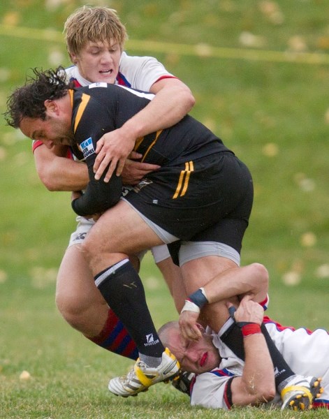 Calgary Hornets captain Dustin MacPherson is wrapped up by Chris Ealey (top) and Mark Dewes of the St. Albert firsts in the Labatt&#8217;s Cup provincial final Saturday. The