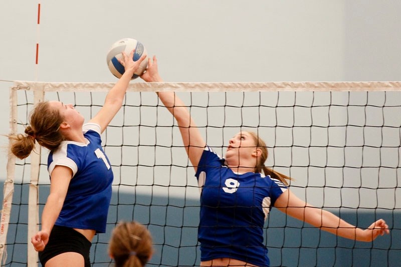 Amber Easthope (left) of the St. Albert Skyhawks and Hailey Lutz of the Paul Kane Blues battle for the volleyball in Wednesday&#8217;s metro Edmonton premier conference match 
