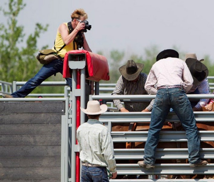 Gazette staff photographer April Bartlett positions herself near the action in an attempt to capture a saddle bronc event at the Rainmaker Rodeo.