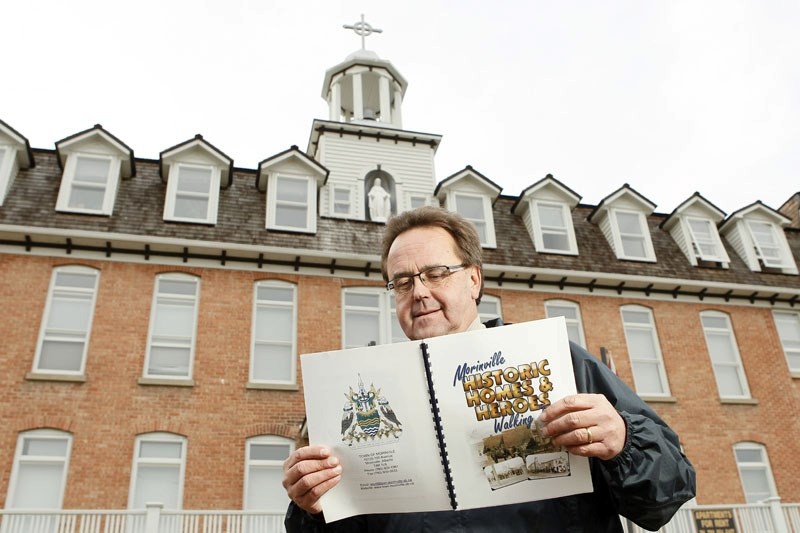 Morinville Mayor Lloyd Bertschi examines his town&#8217;s Historic Homes walking tour book in front of the former Notre Dame convent. The convent is one of only two buildings 