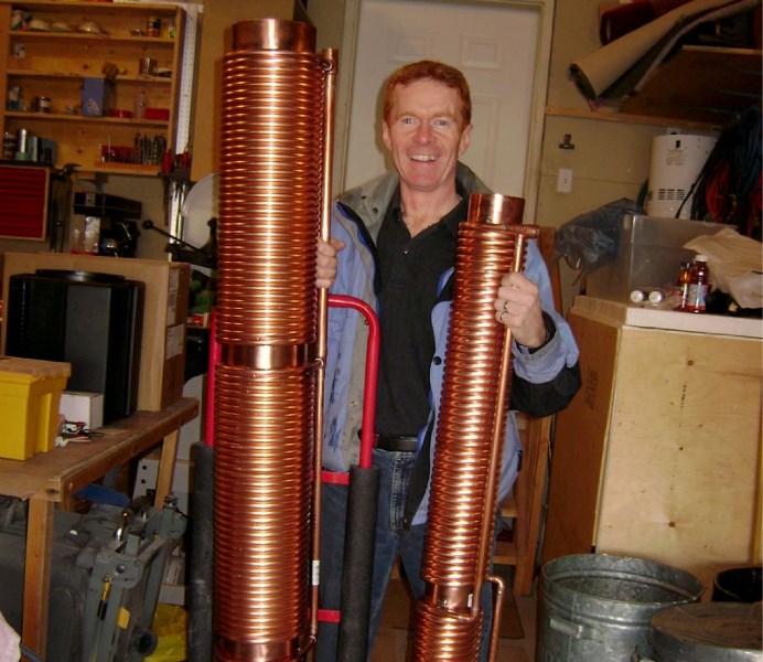 Engineer David Morrow poses with two large drain heat recovery units. These radiator-like devices can siphon waste heat from the water that goes down your drain