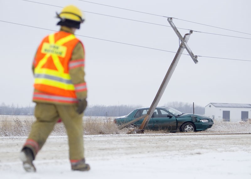 A Sturgeon County Fire and Rescue member walks past an accident scene along Township Road 554 near Cardiff on Saturday. The driver of a Pontiac Grand Am lost control on icy