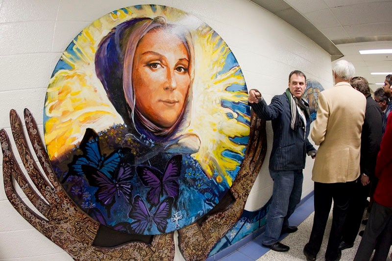 Lewis Lavoie (in grey next to painting) and art teacher Pam Wilman worked together with 120 ESSMY students to complete a mural honouring the school&#8217;s patron saint