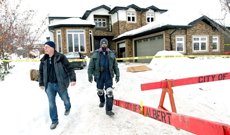 OWNER CHARGED – Fire investigators emerge from the home at 19 Oak Point on Sunday