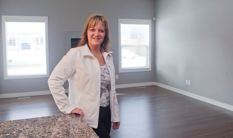 BEFORE – Home staging consultant Connie Williamson stands in a newly built home that she has been hired to stage with furniture and decorations that will aid in raising