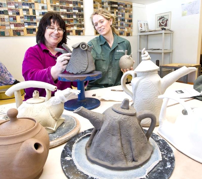 TEMPTING TEAPOTS – Potters Linda Willard (left) and Elene Hartman work on their teapots for the annual St. Albert Potters Guild spring sale