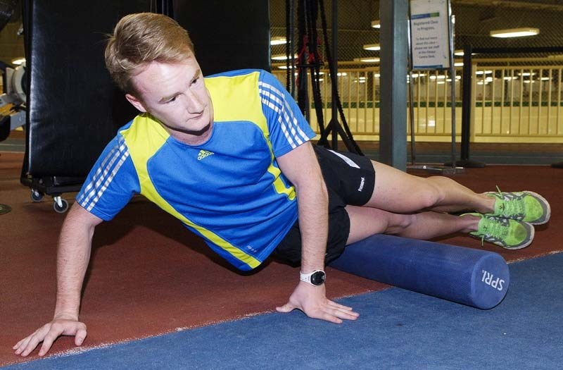 ROLLER REHAB – St. Albert triathlete Kiel Klauwers uses a foam roller to massage his IT band. Runners often suffer IT band problems but these can be addressed through