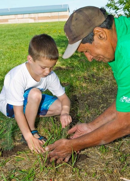 DEEP ROOTS – Leo Nickerson Grade 1 student Doyle Michaels and city summer employee Richard Perreault plant a tree at Larose Park on Wednesday as part of Arbour Day