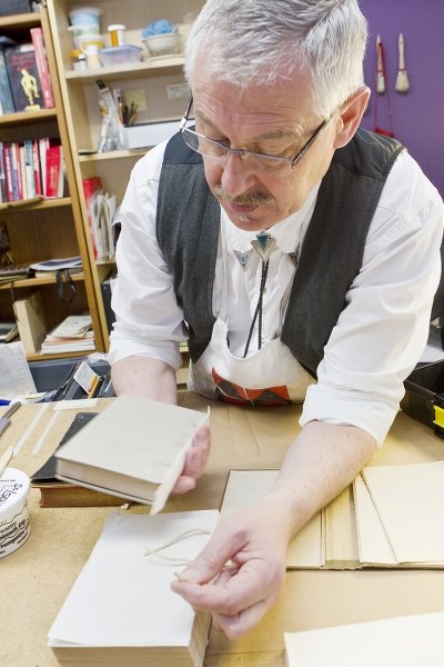 CAREFUL CRAFTSMAN – Barry Bailey examines a book that he recently sewed back together.