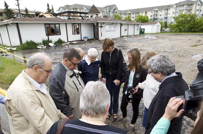 POLICE SUSPICIOUS – Members from the Morinville St. Andrews Anglican Church say a prayer Sunday morning after an early morning fire destroyed their church.