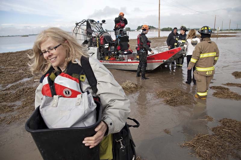 LONG NIGHT – Jane Miller of High River is rescued Friday morning after she and a group of people spent the night on a stack of building material to escape the surging flood