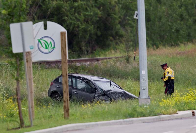 INVESTIGATION CONTINUES – An Edmonton Police Service traffic specialist examines a car that plummeted off an Anthony Henday overpass near Campbell Business Park on Monday