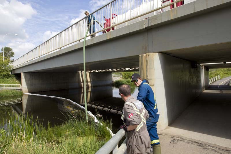 RIVER SPILL – A response team suctions up an unknown substance on the Sturgeon River Thursday at the Boudreau Bridge. Officials are still awaiting test results to determine