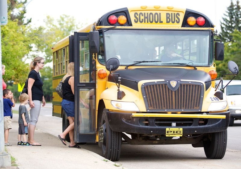 ALL ABOARD &#8211; A group of students and their parents embark the school bus for the inaugural ride of the children&#8217;s school careers.