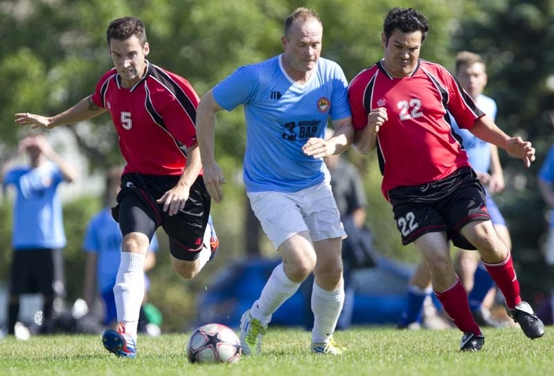 SPLITTING THE DEFENCE &#8211; Michael Markey of SA City pushes the ball past Marco Antonio (left) and Christian Razo of the Rummies in the St. Albert Men&#8217;s Soccer