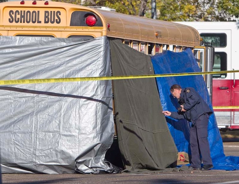 CHILD KILLED – An RCMP photographer examines the scene of a fatality involving a six-year-old boy and a school bus at the intersection of Sir Winston Churchill Avenue and