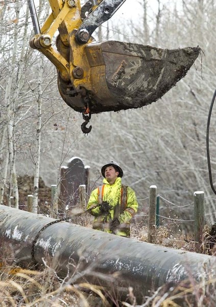 GO WITH THE FLOW – Sergei Ivanitsky gets ready to hook up a chain to help lift a waterpipe Saturday. Construction work has been ongoing on a new waterline down Poundmaker