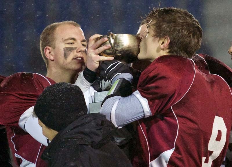 SEALED WITH A KISS &#8211; Bellerose Bulldogs quarterback Trace Stuht kisses the championship trophy as teammate Tyler Fletcher looks on after Thursday&#8217;s 21-17 victory