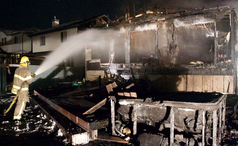 EXTENSIVE FIRE DAMAGE – A firefighter soaks the exterior of a Heritage Lakes home that went up in flames on Friday night. Officials say the cause was a heat lamp placed under 