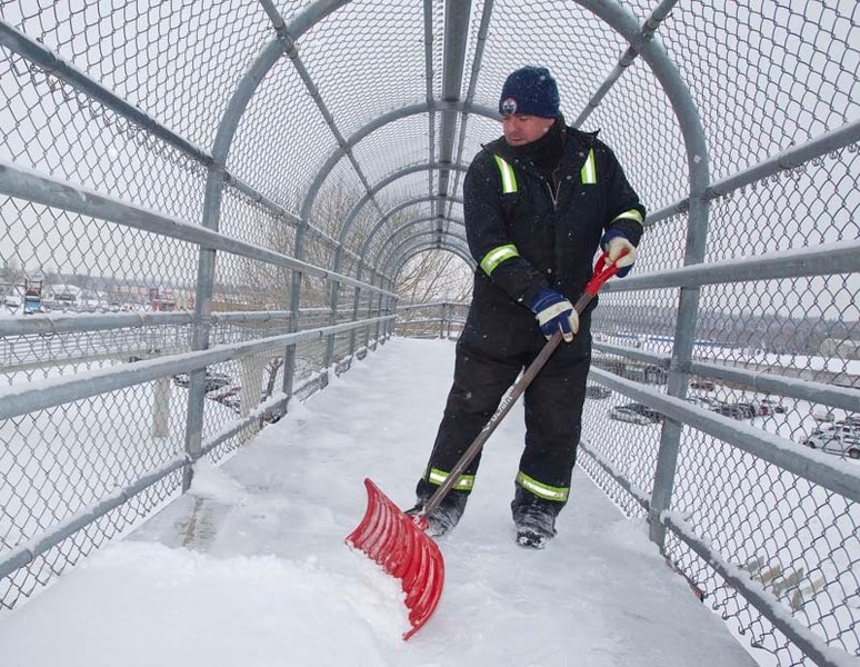 SNOW MAN – City employee Derek Merchant shovels snow off the pedestrian walkway over St. Albert Trail on Friday to prevent deep snow from blocking the path. Snowfall levels