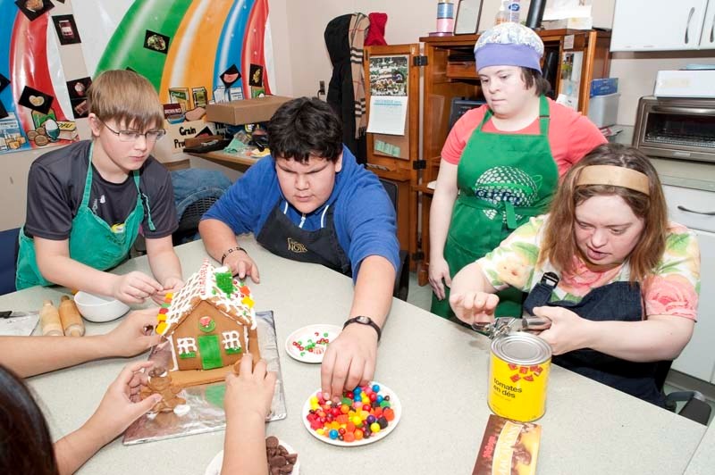HELPING HANDS – Camilla School students Jordan Lopushinsky (left) and Jorel Paul (in blue) help Chrysalis Society clients Ann Methunhall (with cap) and Jill Capham (with can