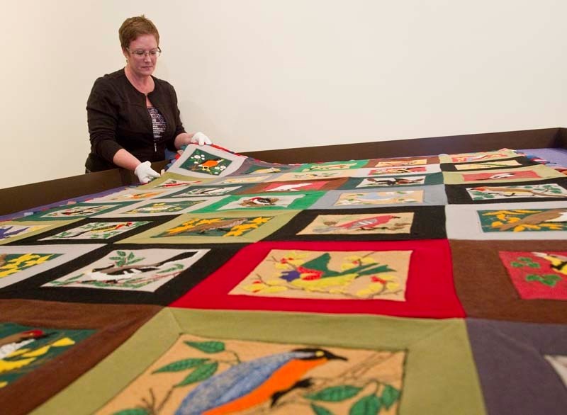 QUILT EXHIBIT – Curator Joanne White prepares a quilt for display as part of the Piece Makers exhibit.