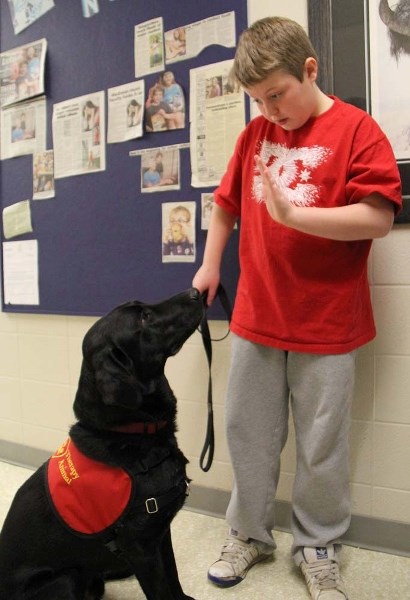 IN CONTROL – Keenooshayo student Brendan Lindbeck commands three-year-old service dog Lewis to sit and stay. Lindbeck&#8217;s self-confidence has grown substantially since he 