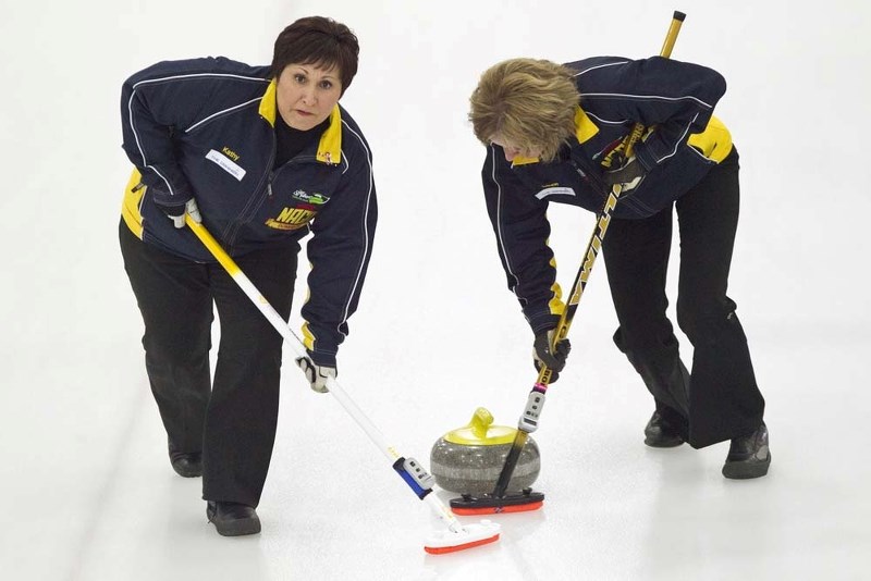 BRINGING IT HOME &#8211; Kathy Piper checks out the line while Laurie Schreiner polishes the ice for a rock thrown by Cindy Bobowik with the Lauren Jenkyns rink in the