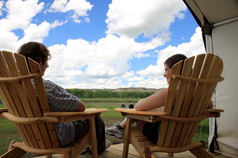 AHHH – Comfortable campers relax on the front porch of a wall tent comfort camping unit in Dinosaur Provincial Park.