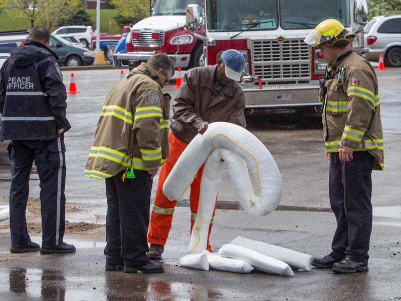 SPILL RESPONSE – St. Albert fire service members and city crews place absorbent booms around an area in the east parking lot of Canadian Tire on Thursday after it was