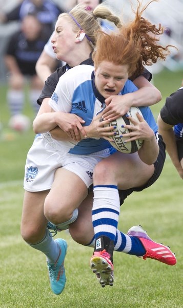 WRAPPED UP &#8211; Kendall DeWitt of the Paul Kane Blues hangs onto the ball while tackled from behind in Tuesday&#8217;s metro Edmonton division two rugby final against the