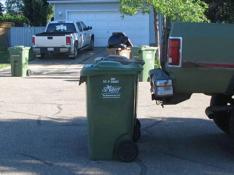 TOO CLOSE – Two garbage bins placed too close to the bumper of a pickup truck. The driver of the garbage truck cannot safely pick up the bins without damaging the pickup