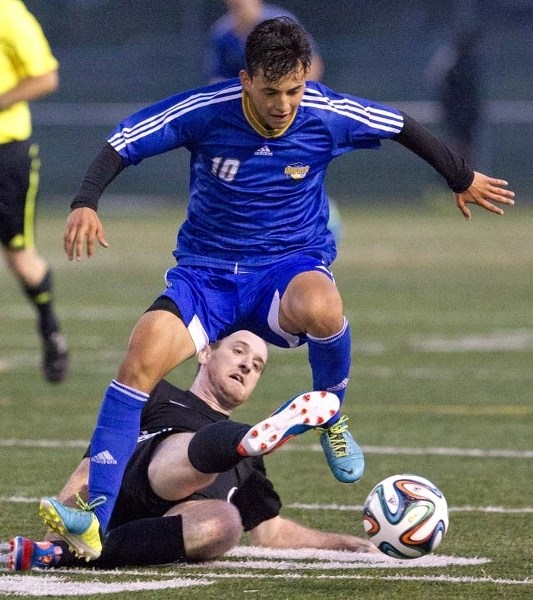 BALL BATTLE – St. Albert Impact player Carlos Pacino jumps over a KC Trojans defender during an evening game at Riel Turf Field Thursday. The Impact beat the Trojans 2-0.