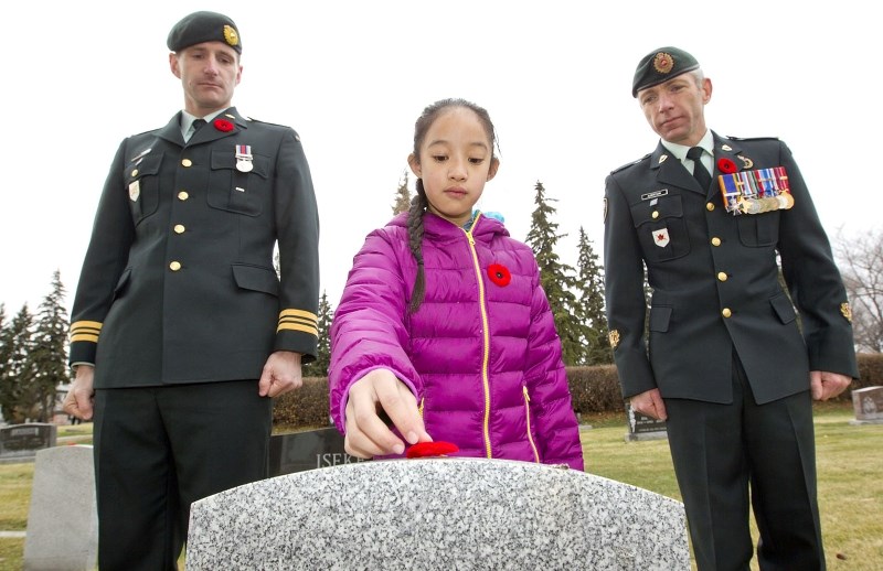 Bertha Kennedy students place poppies on the graves of soldiers in the St. Albert Catholic Parish Church cemetery as part of the No Stone Left Alone campaign – an Alberta