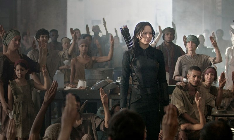 Citizens of one of the downtrodden districts show their allegiance to Katniss with a salute.