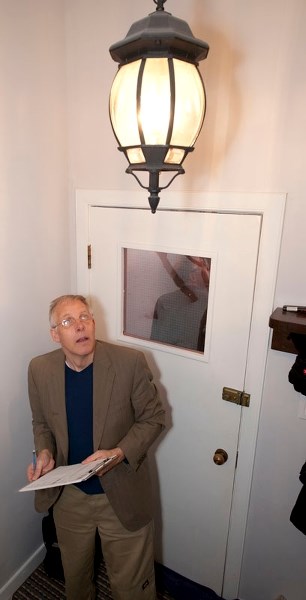 SEARCHING FOR SAVINGS – Energy auditor Godo Stoyke of C Returns inspects a light during an audit of the Sokolic home earlier this month. The light was incandescent and could
