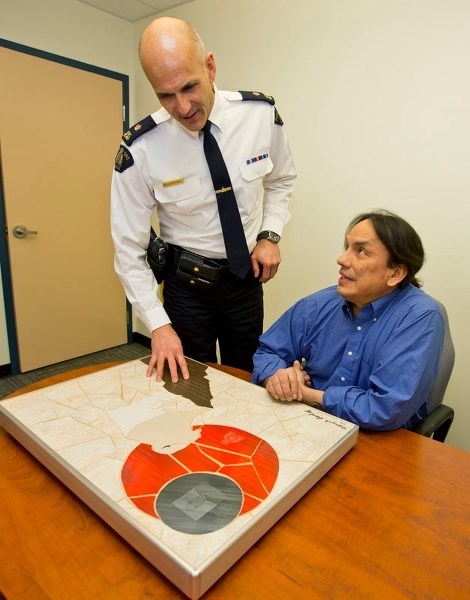 An appreciative St. Albert RCMP detachment head Insp. Kevin Murray looks over the donated piece of art that Wayne Ashley donated as a tribute to fallen Const. David Wynn.