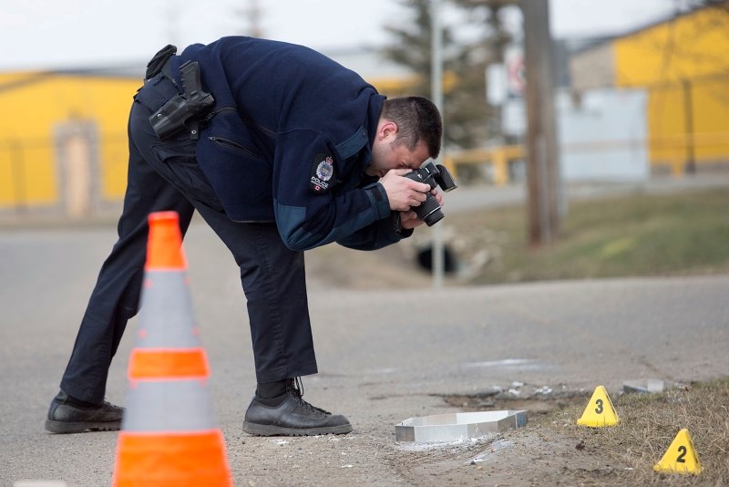 RELATED CRIME SCENE &#8211; An officer with Edmonton Police Services takes photos of tracks in the dirt at a crime scene