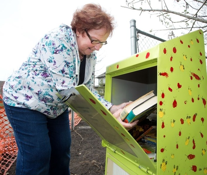 June Bailey restocks a community book box near the Sturgeon Heights School on Friday. As a result of it&#8217;s popularity