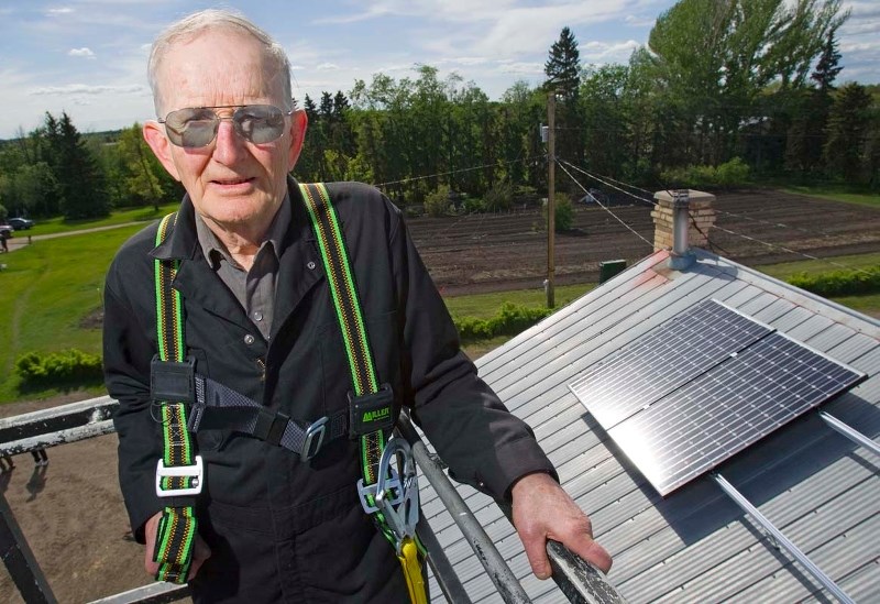 SUN HARVEST — John Bocock oversees the installation of solar panels on the roof of his dairy barn in this 2010 photo. Bocock now has 24 of these modules on the barn