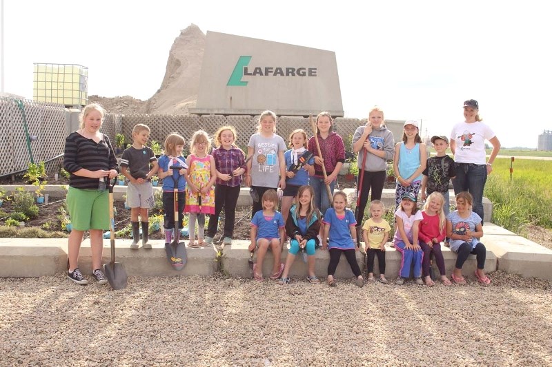 The Morinville Girl Guides pose in front of their pollinator garden at the Lafarge Concrete Plant with Michelle Sevenhuysen.