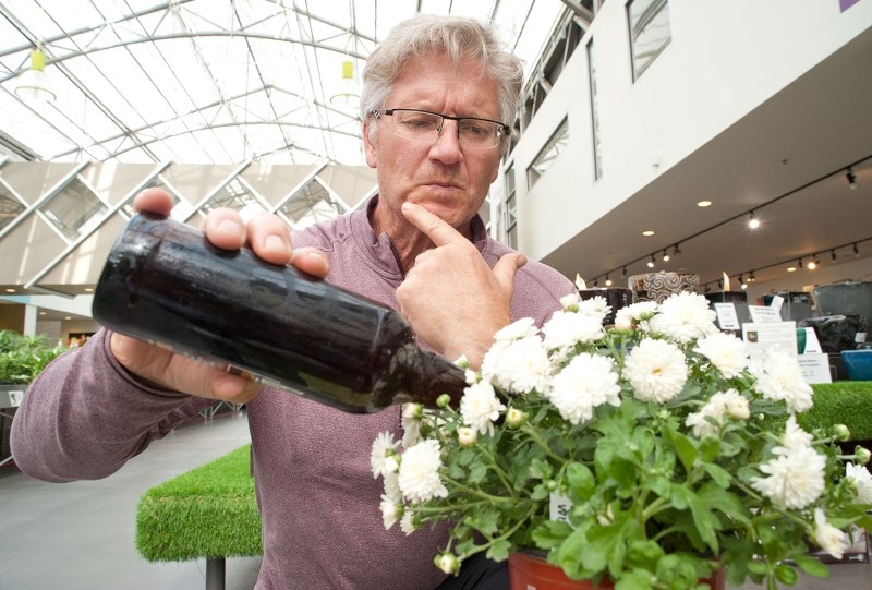 GOOD IDEA? – Enjoy Centre co-owner Jim Hole pretends to water a plant with beer