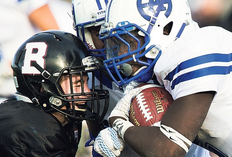 HEAD-ON COLLISION – Colton Meronyk of the Bellerose Bulldogs butts heads with a Harry Ainlay Titan in metro Edmonton high school football Thurday at Riel Recreation Park. The 