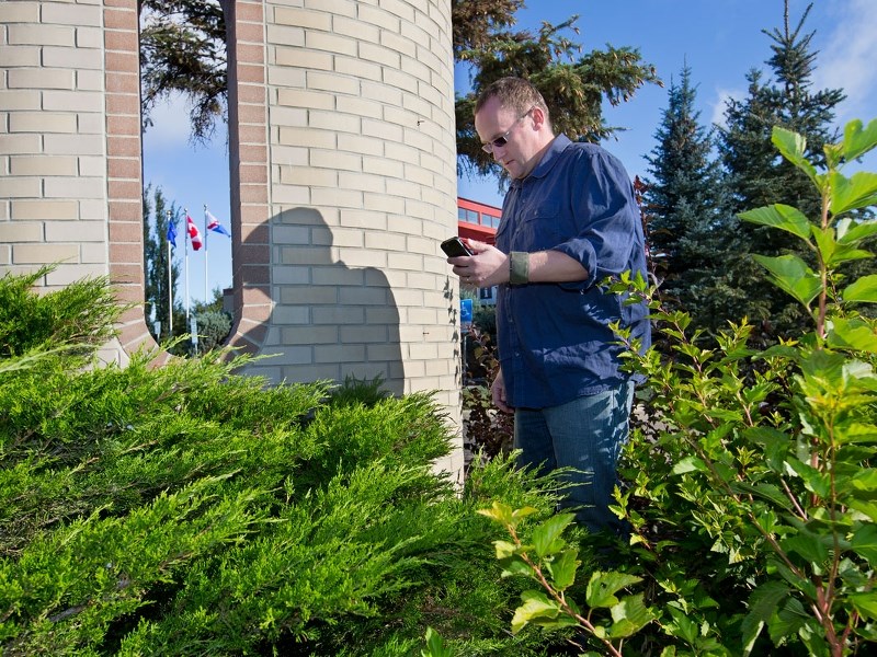 Ron Harvie uses his smart phone and geocaching app to loacte a cache in St. Albert.