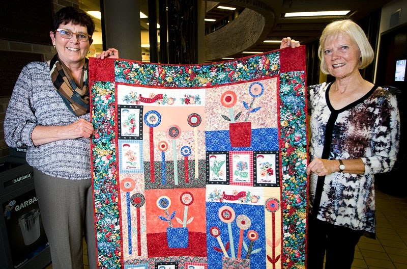 Liz Henderson and Dorothy Koblun show off one of the many majestic quilts that will be on display during the Quilters&#8217; Guild&#8217;s 35th anniversary exhibit entitled