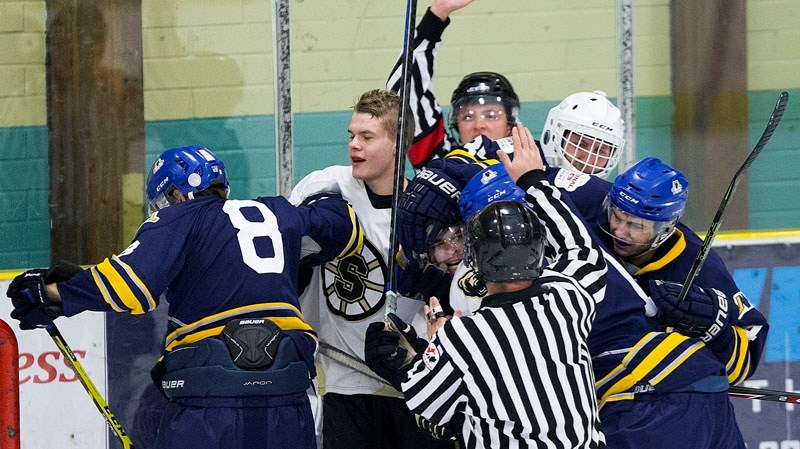 MIXING IT UP – The St. Albert Merchants and Strathcona Bruins hug it out as referee Kurtis Eyklebosh and linesman Brad Scott try to maintain order in Friday&#8217;s junior B