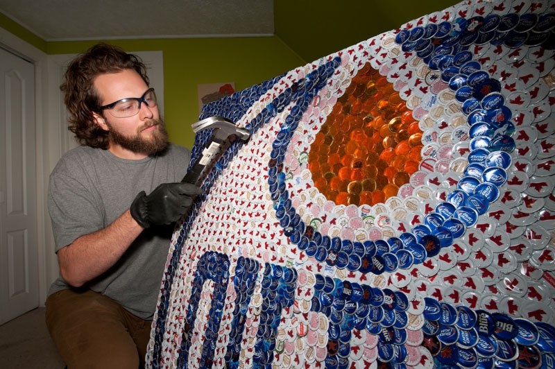 FINISHING TOUCHES – Former St. Albert resident Jeff Meszaros hammers some edges flat on a large Edmonton Oilers mural he made from bottlecaps. Meszaros collects the caps and