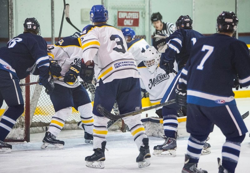 PUCK RETRIEVAL – St. Albert Merchants netminder Ty Clelland scrambles to find the puck against the Morinville Jets as players from both teams and the referee join in the